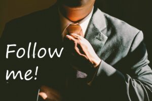 The words "Follow me" over a pic of a man straightening his tie
