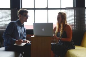 man and woman sitting with a laptop between them