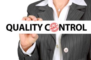 A woman in a suit holding a sign saying Quality Control